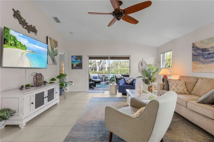 Tiled living room featuring ceiling fan and vaulted ceiling
