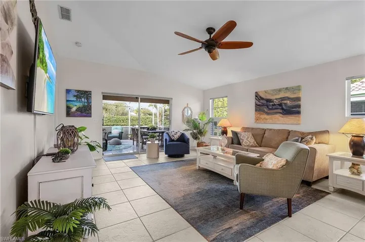 Tiled living room with vaulted ceiling, plenty of natural light, and ceiling fan