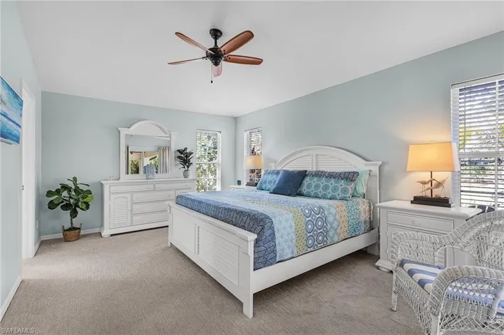 Carpeted bedroom featuring multiple windows and ceiling fan