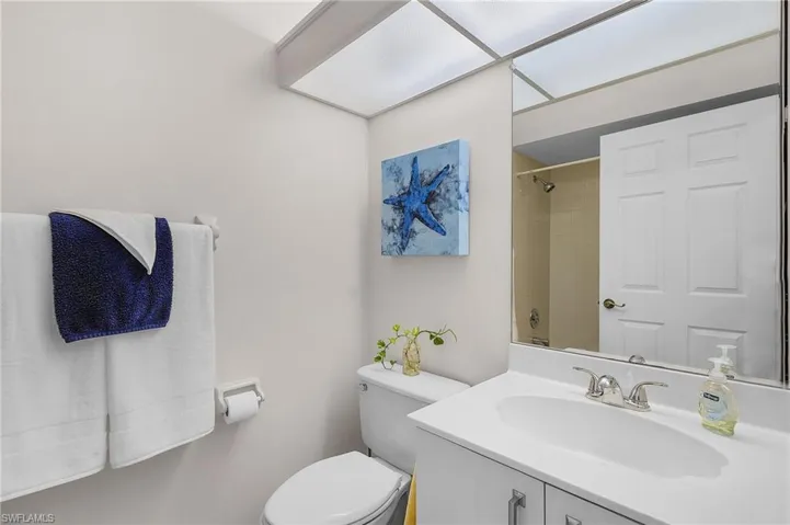 Bathroom with tiled shower, vanity, and toilet