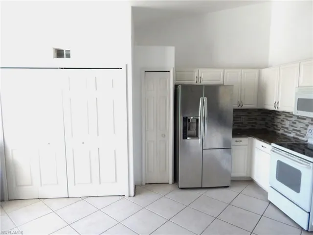 Kitchen with white cabinets, white appliances, and light tile patterned floors