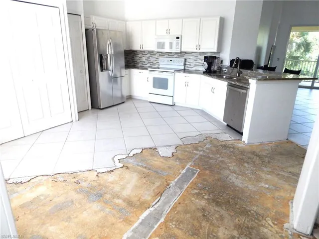 Kitchen featuring backsplash, kitchen peninsula, stainless steel appliances, sink, and white cabinets