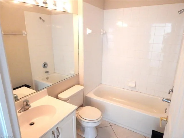 Guest bathroom with tiled shower / bath combo, vanity, toilet, and tile patterned flooring