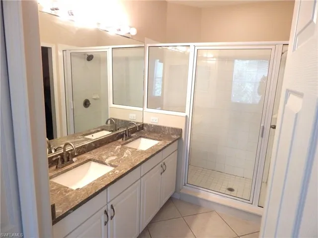 Owners Bathroom featuring tile patterned floors, a shower with door, and vanity