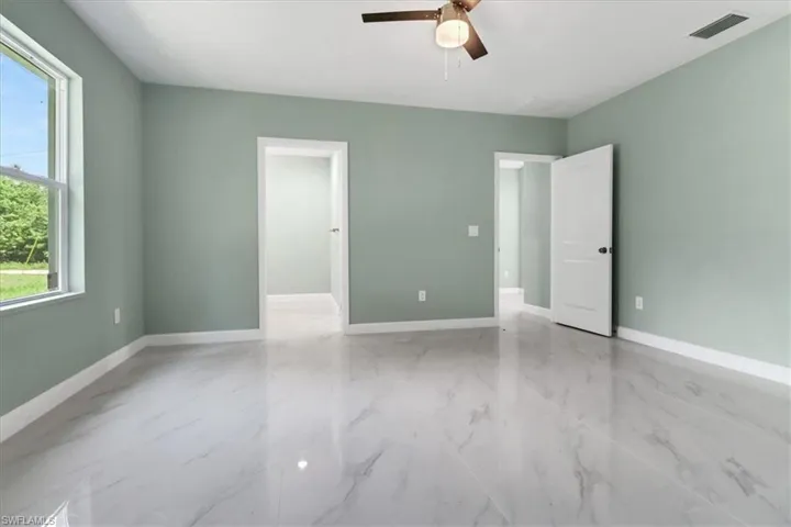 Unfurnished room featuring ceiling fan and a wealth of natural light