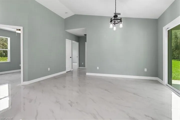 Unfurnished room with a notable chandelier and lofted ceiling