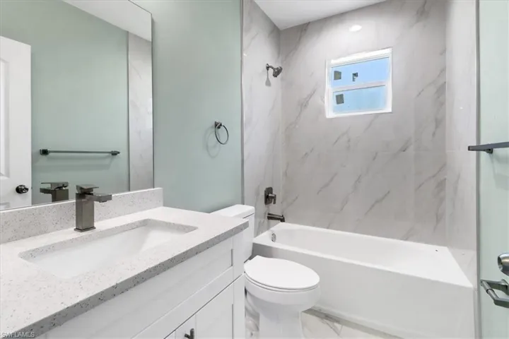 Full bathroom with tiled shower / bath combo, vanity, and toilet