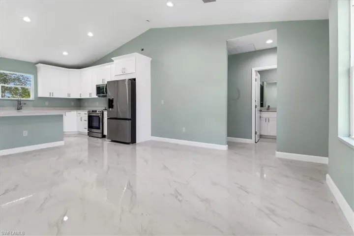 Kitchen with white cabinets, sink, stainless steel appliances, and vaulted ceiling