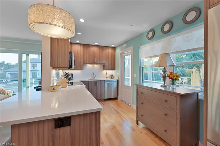 Kitchen with pendant lighting, brown cabinets, recessed lighting, appliances with stainless steel finishes, and a peninsula