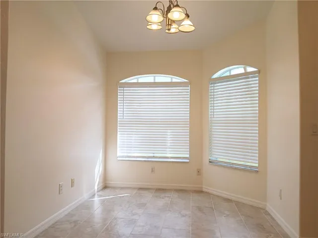 Unfurnished room with a chandelier and light tile flooring