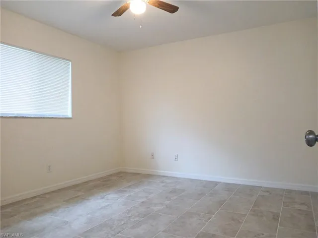 Empty room with ceiling fan and light tile floors