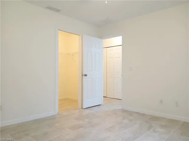 Unfurnished bedroom with a spacious closet, a closet, and light tile floors