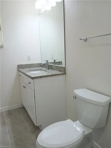 Bathroom with vanity with extensive cabinet space, toilet, and tile floors