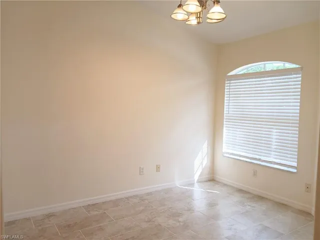 Tiled spare room with an inviting chandelier