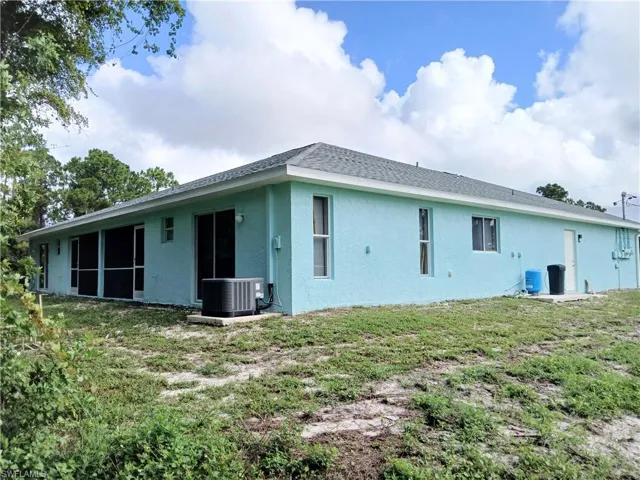 Back of property with a yard and central AC