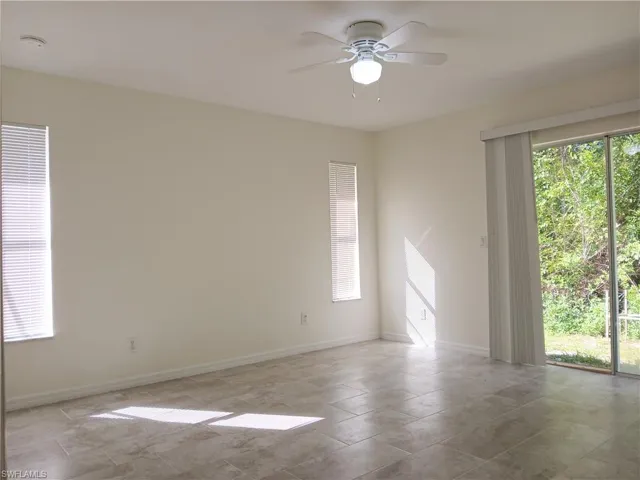 Tiled spare room featuring ceiling fan