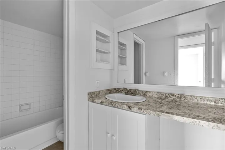 Full bathroom featuring tiled shower / bath, vanity, and toilet
