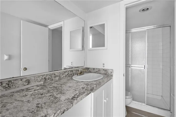 Bathroom featuring tile patterned flooring, vanity, toilet, and an enclosed shower