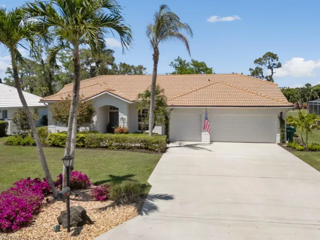 View of front of property with a tile roof, concrete driveway, a front yard, and a garage