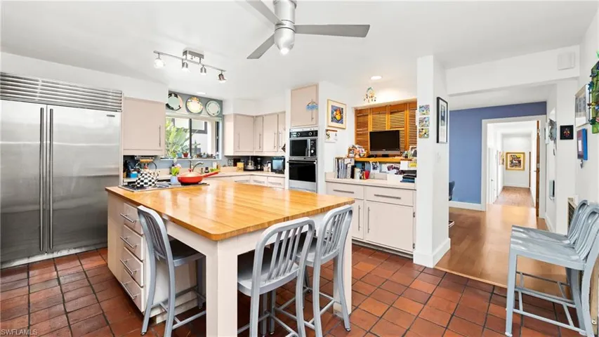 Kitchen featuring butcher block countertops, stainless steel built in refrigerator, a breakfast bar, a center island, and dark tile patterned flooring