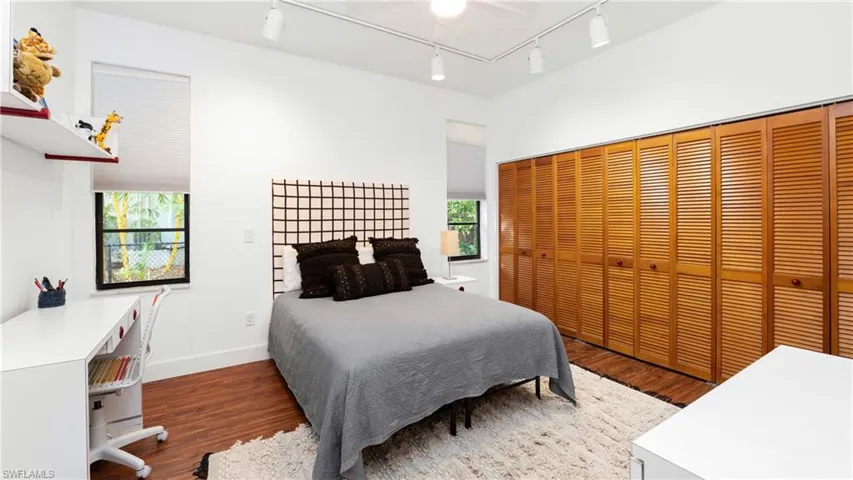 Bedroom featuring multiple windows, wood finished floors, and rail lighting
