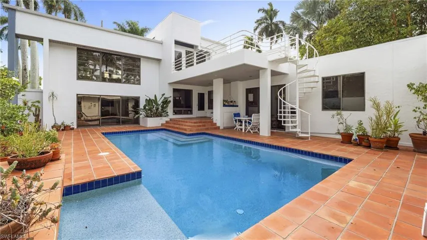 Rear view of property featuring stucco siding, a patio area, an outdoor pool, and stairs