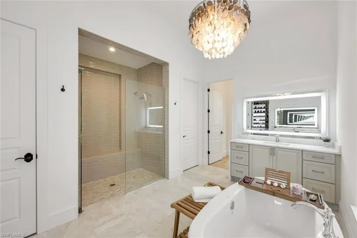 Full bathroom with a soaking tub, tiled shower, vanity, and a chandelier