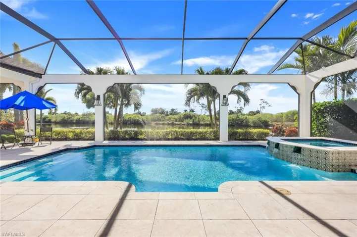 View of swimming pool featuring a patio area, a lanai, a pool with connected hot tub, and a water view