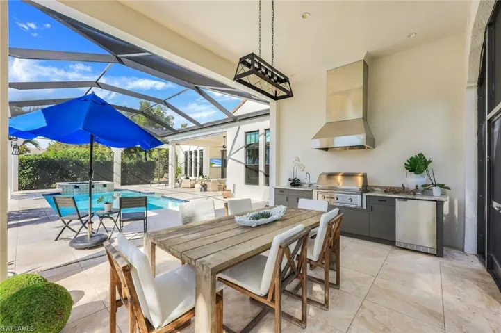 View of patio / terrace featuring area for grilling, outdoor dining space, glass enclosure, and a pool with connected hot tub