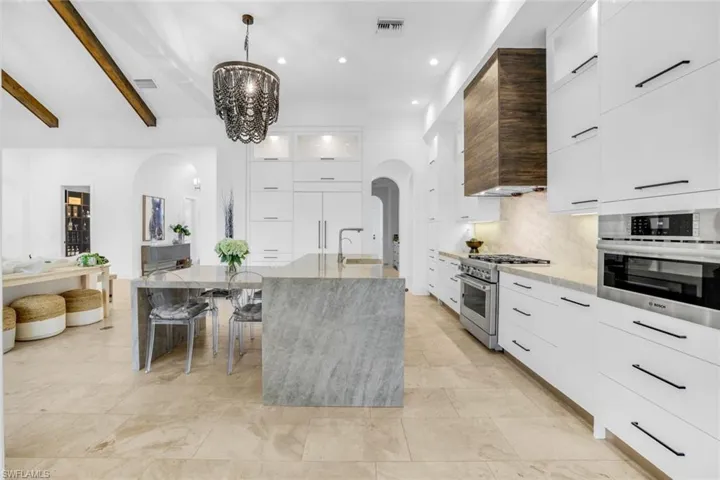 Kitchen with white cabinets, modern cabinets, arched walkways, beam ceiling, and open floor plan