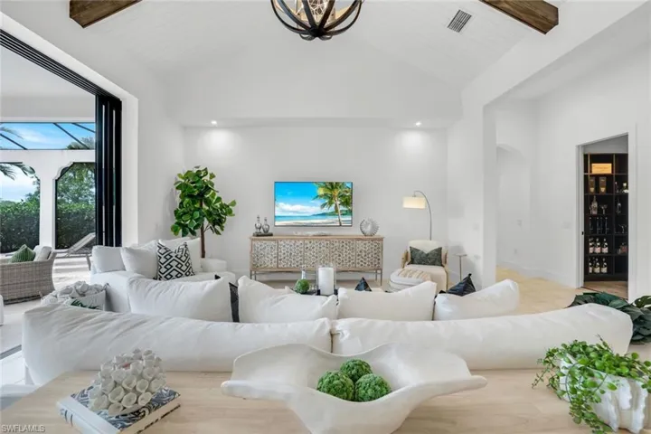 Living area with beam ceiling, arched walkways, and high vaulted ceiling