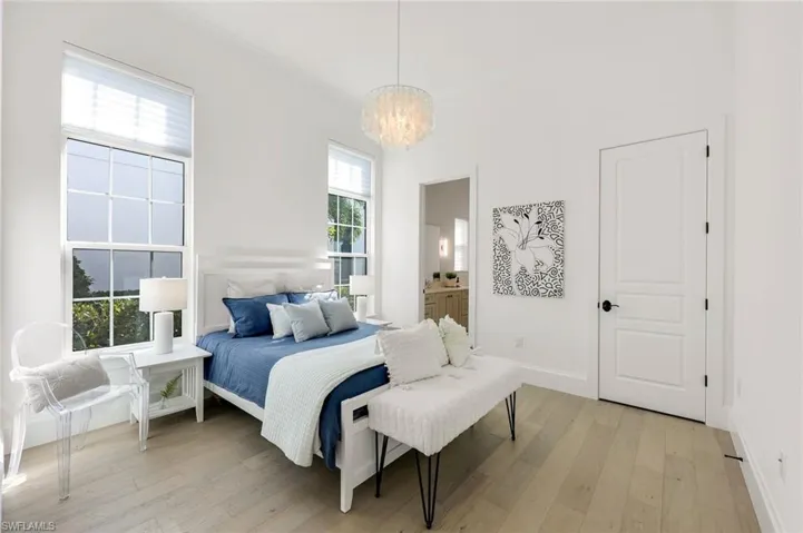 Bedroom featuring a chandelier, light wood-style floors, and ensuite bathroom