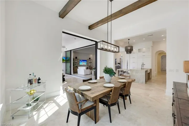 Dining space featuring arched walkways and beamed ceiling