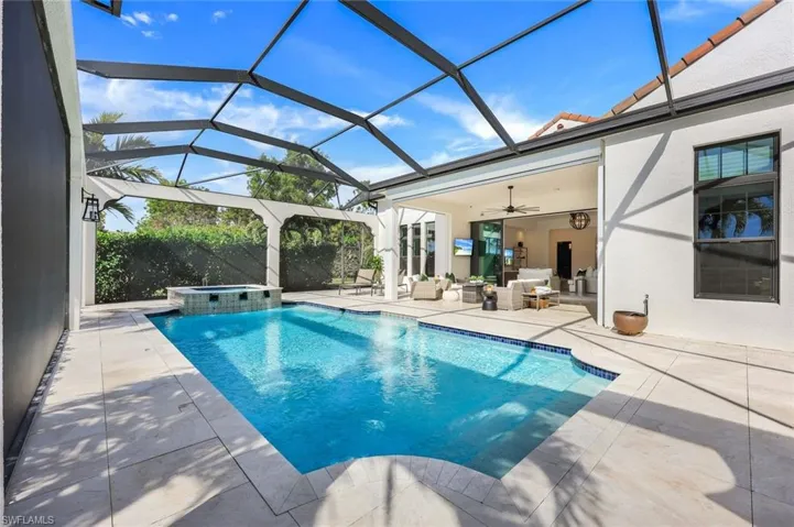 View of pool with an outdoor hangout area, a patio, ceiling fan, and glass enclosure