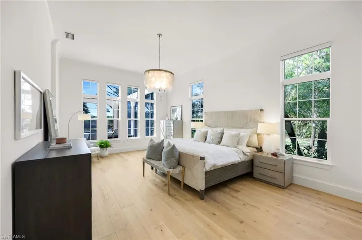 Bedroom featuring light wood-type flooring, multiple windows, and a chandelier