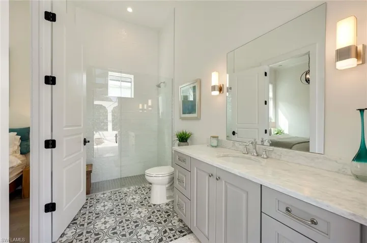 Ensuite bathroom with vanity, a walk in shower, and light tile patterned floors