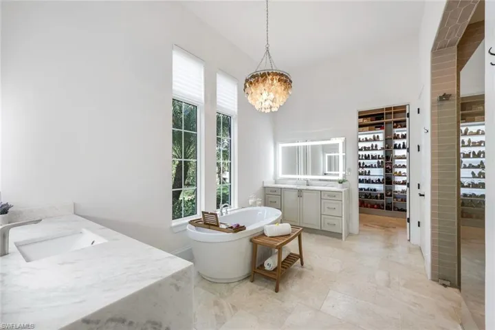 Full bathroom with vanity, a freestanding bath, a chandelier, and a spacious closet