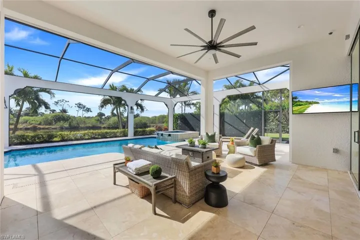 View of pool featuring a patio area, a lanai, a ceiling fan, and a pool with connected hot tub