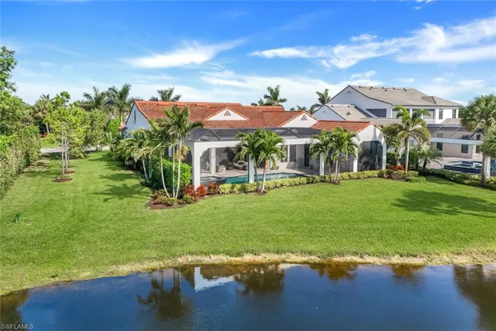 Back of house featuring an outdoor pool, a tiled roof, a water view, and a yard