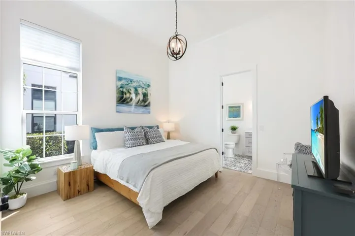 Bedroom featuring light wood-type flooring, a chandelier, and connected bathroom