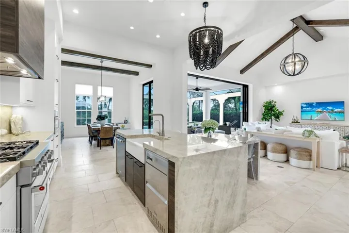 Kitchen featuring a chandelier, hanging light fixtures, light stone countertops, stainless steel appliances, and recessed lighting