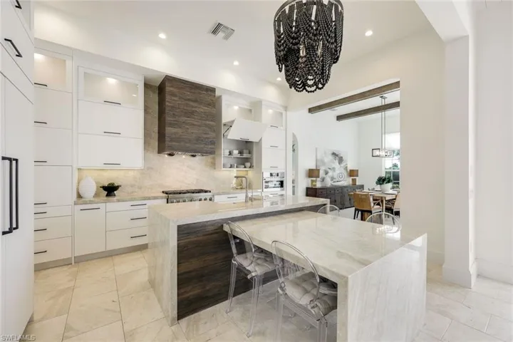 Kitchen with modern cabinets, decorative backsplash, arched walkways, a breakfast bar area, and stainless steel oven