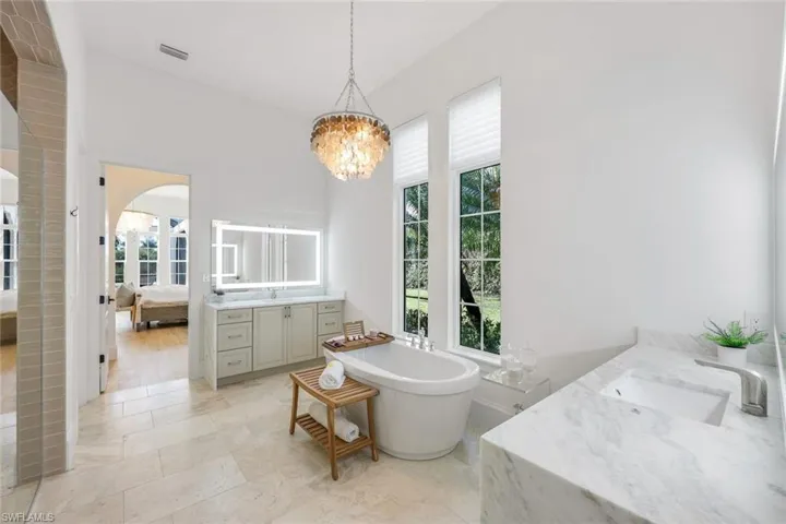 Ensuite bathroom featuring vanity, plenty of natural light, a freestanding bath, and a chandelier