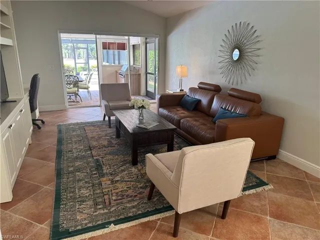 Living room with a desk, lofted ceiling, and light tile patterned floors