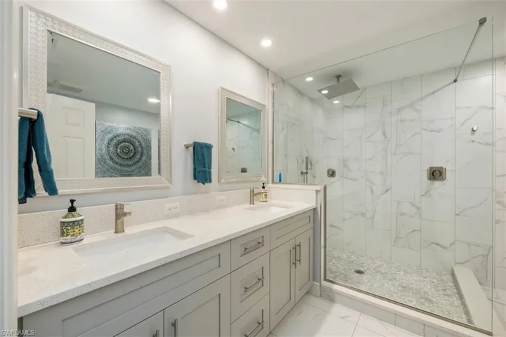 Guest Bathroom with a marble finish shower, double vanity, and recessed lighting