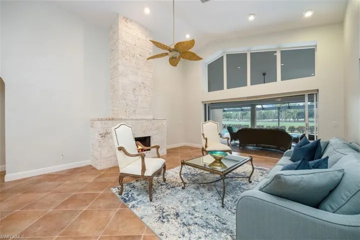 Living room featuring high vaulted ceiling, a fireplace, light tile patterned floors, ceiling fan, and recessed lighting