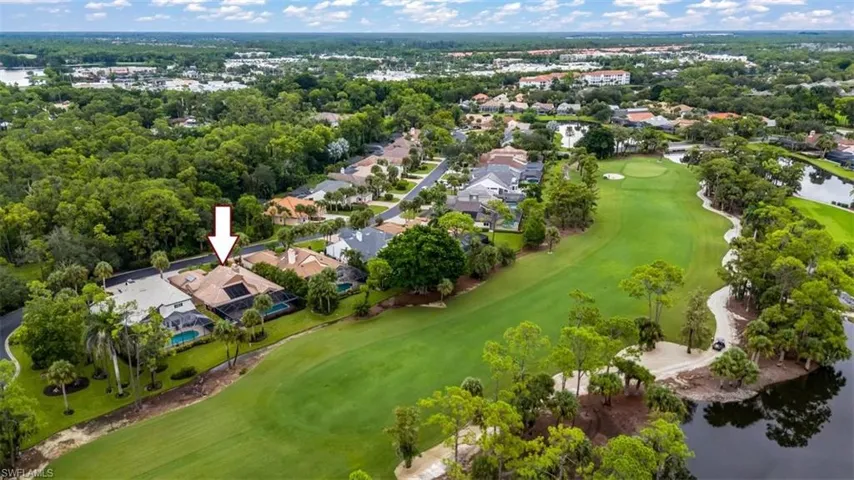 Aerial perspective of suburban area featuring a golf course and a nearby body of water