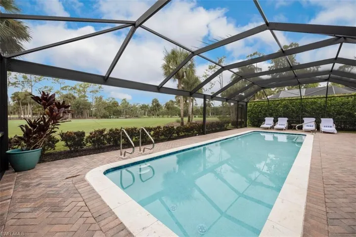 Outdoor pool featuring glass enclosure, a sunroom, a patio area, and a lawn