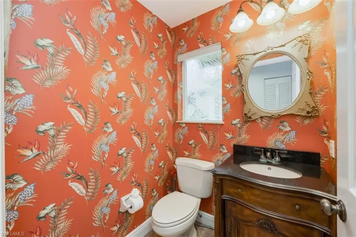 Half bath with wallpapered walls, vanity, and a chandelier