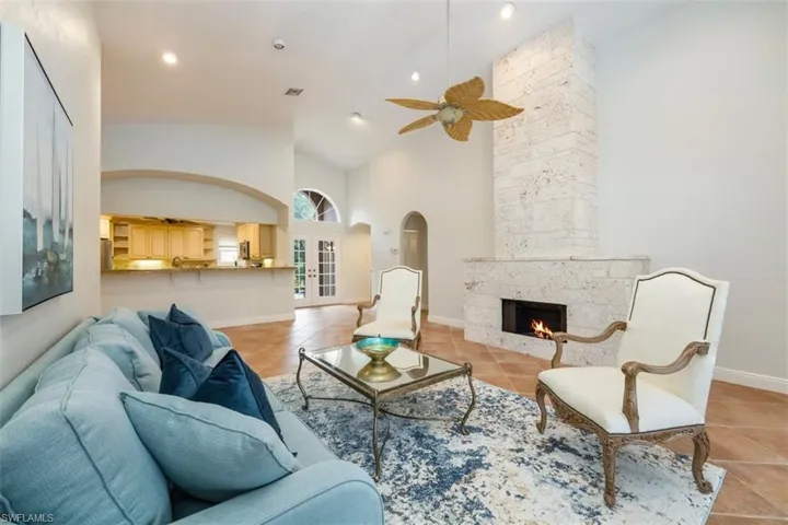 Living area with a ceiling fan, high vaulted ceiling, light tile patterned flooring, a large fireplace, and recessed lighting